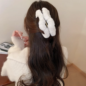 Detailed view of white plush faux fur hair claw clip styled on long hair for winter