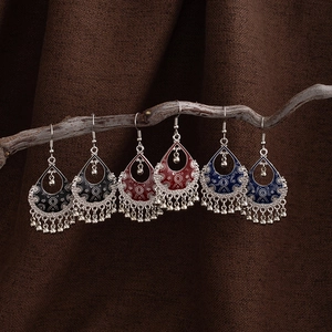 Detail of bohemian drop earrings in black, red, and blue with bead tassel charms