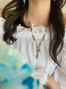 Detail of colorful turquoise beaded necklace and teardrop pendant on a model