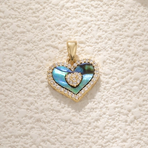 Close-up of heart-shaped gold necklace pendant with abalone shell and tiny diamonds