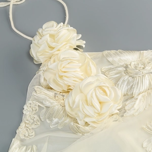 Close-up of 3D floral decoration on white halter dress with satin and mesh fabric