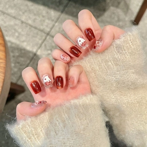 Detailed view of handmade red cat-eye press-on nails with strawberry cake and bow designs