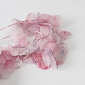 Detail van roze chiffon bloemenband met gelaagde bloemblaadjes en doorschijnende stof