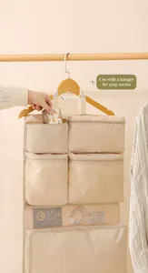 Dettaglio dell'organizzatore da viaggio sospeso beige con tasche a zip su supporto in legno