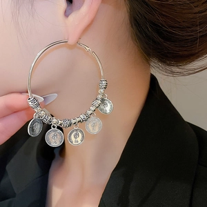 Detail view of retro silver hoop earrings featuring coin pendants with Queen Elizabeth relief