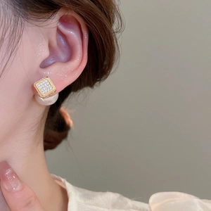 Close-up of elegant square zircon stud earrings with white pearl drop on model
