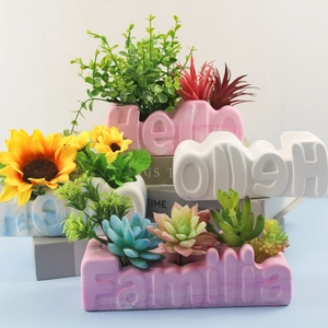Detailed view of marble-textured Hello and Familia letter-shaped plaster succulent planters