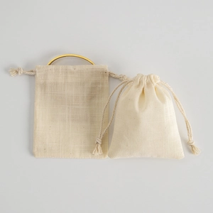 Detail of beige cotton linen drawstring jewelry pouches with a gold ring insert