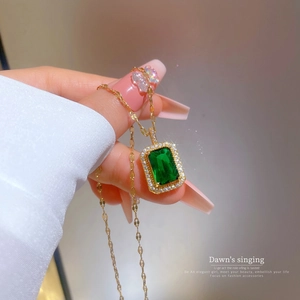 Detailansicht eines quadratischen grünen Smaragdanhängers mit Kristallen auf Goldkette
