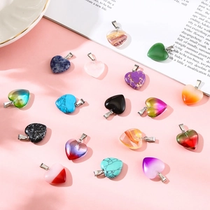 Macro shot of colorful 20mm heart-shaped natural stone pendants on pink background