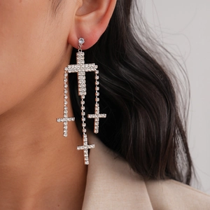 Detailed view of large rhinestone cross earrings on model with sparkling crystal layers