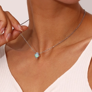 Gros plan d'un collier pendentif opale bleue avec halo de zircon sur le cou du modèle