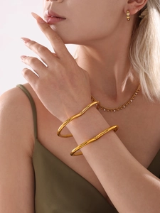 Detailed view of elegant gold wave bangles worn by model for high-end fashion styling