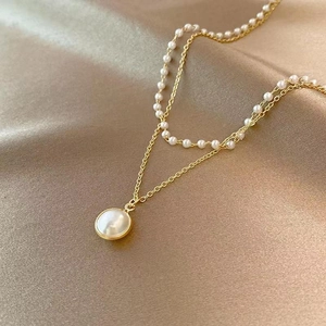Elegant double-layered pearl necklace with golden chain and large round pendant on satin