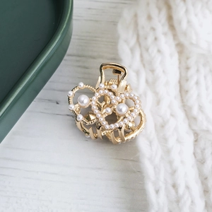 Pince à cheveux cœur dorée élégante avec perles blanches sur un fond minimaliste chic