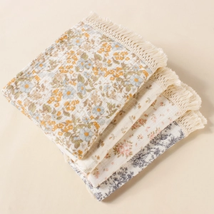 Floral print cotton muslin baby blankets with decorative tassel edges in cream and beige
