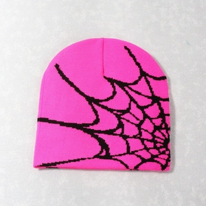 Macro view of bright pink beanie featuring detailed black spider web jacquard knitting