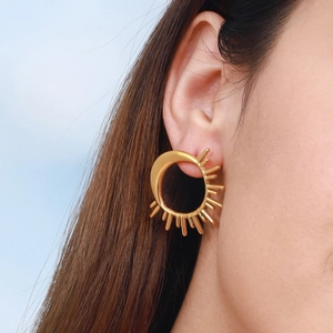 Close-up of a gold 18K plated sun and moon stud earring worn by a model in natural light
