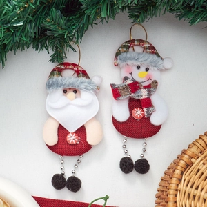 Detailed view of Santa and snowman burlap ornaments hanging on pine needles