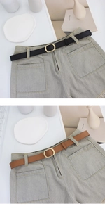 Detail von schmalen schwarzen und braunen Gürteln mit goldener Schnalle auf Jeans