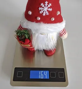 Détail montrant le poids de 164g du gnome de Noël sur une balance électronique