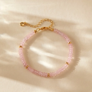 Detail eines rosa Kristallperlenarmbands mit goldenen Distanzstücken und Karabiner