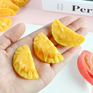 Miniature lifelike yellow dumpling model with realistic pleated texture held in hand