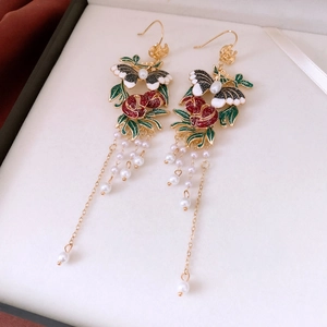 Detail of vintage enamel earrings with red flowers, butterfly and pearl tassels in a box