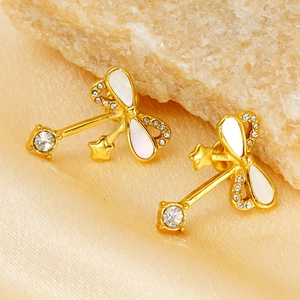 Detailed macro view of gold bow earrings with zircon stars on silk fabric