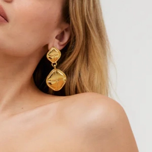 Macro shot of gold double rhombus drop earrings with unique 3D textured metal surfaces