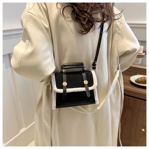 Detail view of black canvas crossbody bag with white plush faux fur trim on trench coat