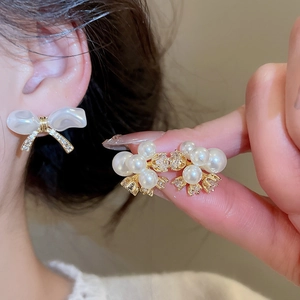 Close-up of elegant gold-plated bow earrings with white pearls and sparkling zircons