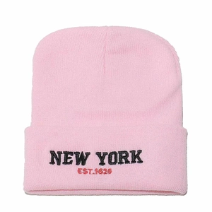 Close-up of pink knit beanie with black New York embroidery and red EST. 1625 text