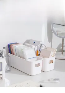 Close-up of white matte plastic storage boxes with side handles for desktop organization