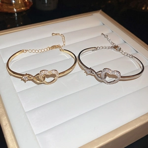 Detail of gold and silver open heart bracelets with zircon inlay on a jewelry tray