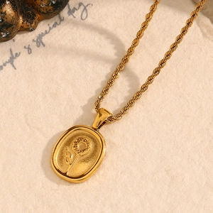 Gros plan d'un pendentif carré doré avec relief tournesol et chaîne maille torsadée