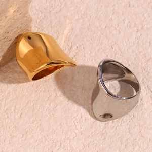 Detail showing irregular wide-surface gold and silver geometric rings on beige stone