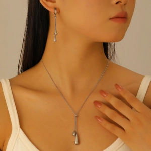 Macro view of silver water drop necklace and long earrings set on model neck