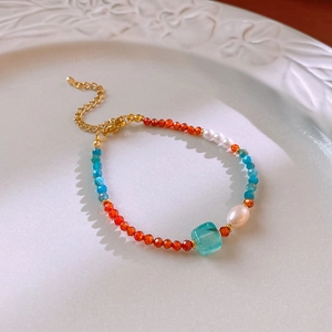 Detail of colorful beaded necklace with freshwater pearls and blue gemstone on a ceramic plate