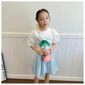 Detail of white t-shirt with green puff sleeves and pleated blue skirt for girls