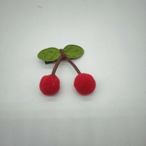 Handmade cherry hair clip with red plush pom-pom fruit and green felt leaves on metal clip