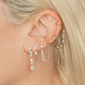 Close-up of gold layered earrings with pear-cut crystals and elegant tassel chains