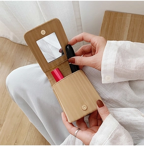 Mini khaki leather lipstick pouch with built-in mirror shown in a handheld lifestyle setting