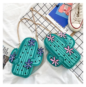 Close-up of cactus shaped crossbody bags with gold metal chain and textured green PU leather