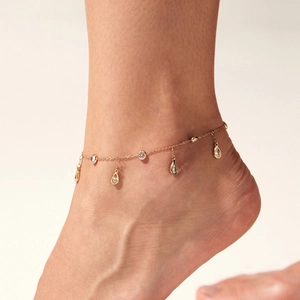 Gold stainless steel anklet with sparkling zircon tassels on a model's ankle
