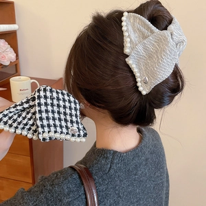 Detail of tweed hair claw clips with pearls shown in elegant hairstyle on a model