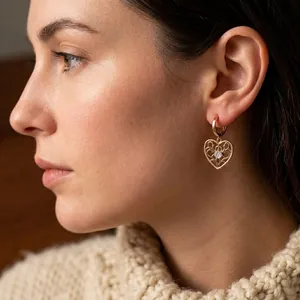 Vintage gold heart key earrings with zircon accents worn by model in cozy lighting
