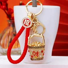 Detail of golden treasure bowl keychain with red rope and sparkling rhinestone ring