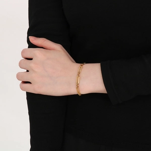 Bracelet chaîne plate en acier inoxydable doré minimaliste porté sur le poignet d'un mannequin