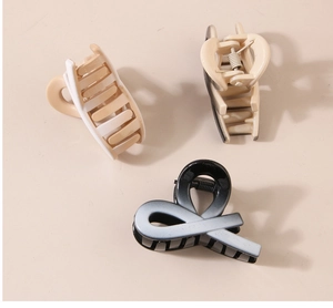 Detailed view of three matte hair claws in cream, brown, and black gradient colors